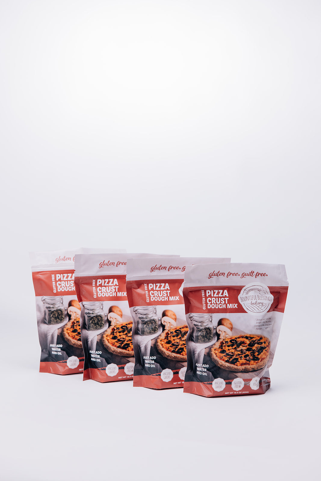 Four stand-up pouches of gluten free pizza crust dough mix arranged in a row on a clean white background.
