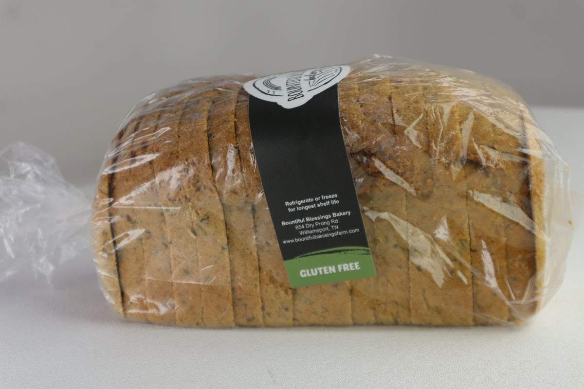 A loaf of gluten-free bread wrapped in clear plastic packaging with a black and green label, set against a plain light gray background.