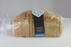 A loaf of sliced gluten-free bread wrapped in clear plastic with a black and white bakery label, set against a neutral gray background.