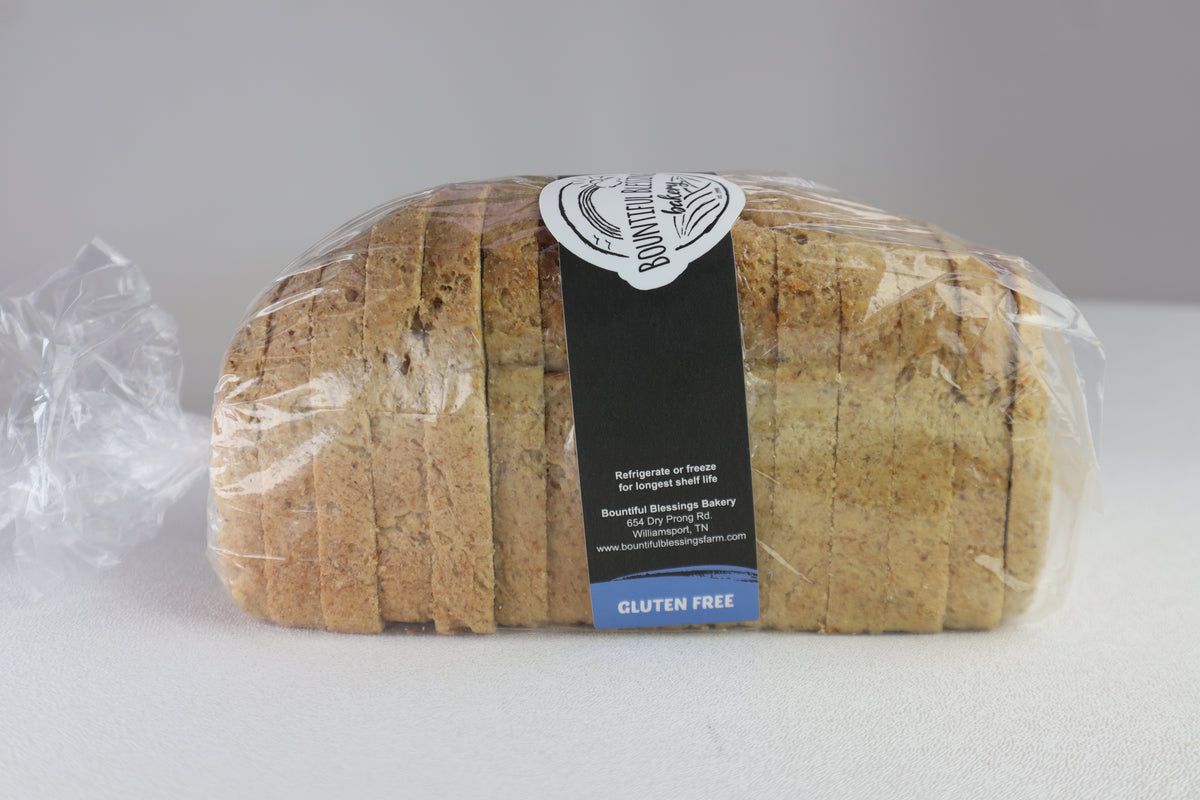 A loaf of sliced gluten-free bread wrapped in clear plastic with a black and white bakery label, set against a neutral gray background.