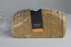A loaf of sliced gluten-free bread wrapped in clear plastic with a black and orange label, set against a plain gray background.