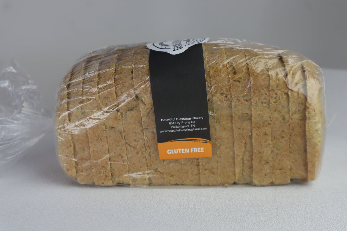 A loaf of sliced gluten-free bread wrapped in clear plastic with a black and orange label, set against a plain gray background.