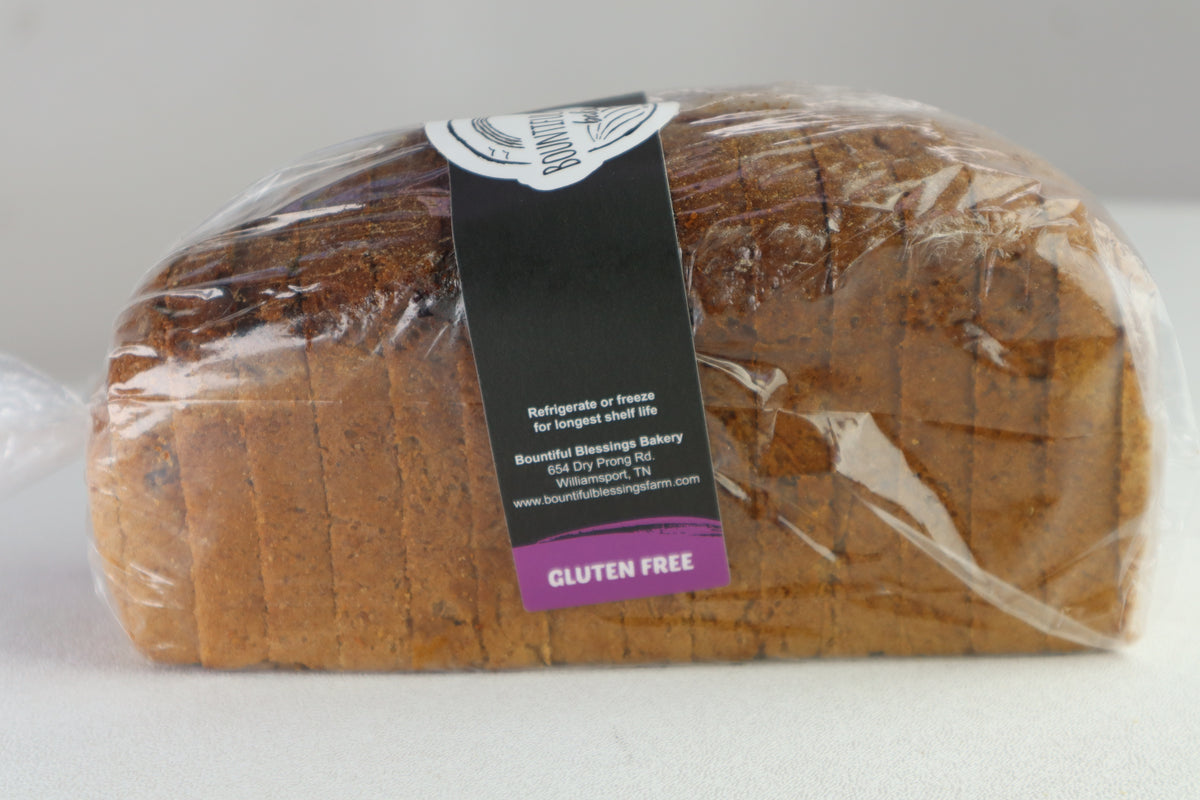 A loaf of gluten-free bread wrapped in clear plastic packaging with a black and purple label. The label reads 'Bountiful Blessings Bakery' and 'Gluten Free'.